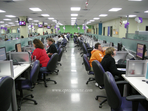 People work at their desks in a call center that sits on a decorative concrete floor.